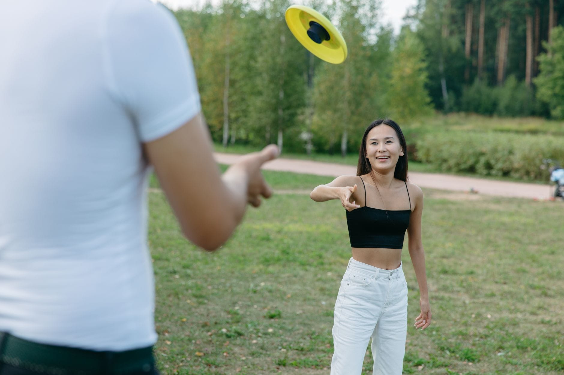 Kobieta rzuca dyskiem frisbee w słoneczny dzień w parku