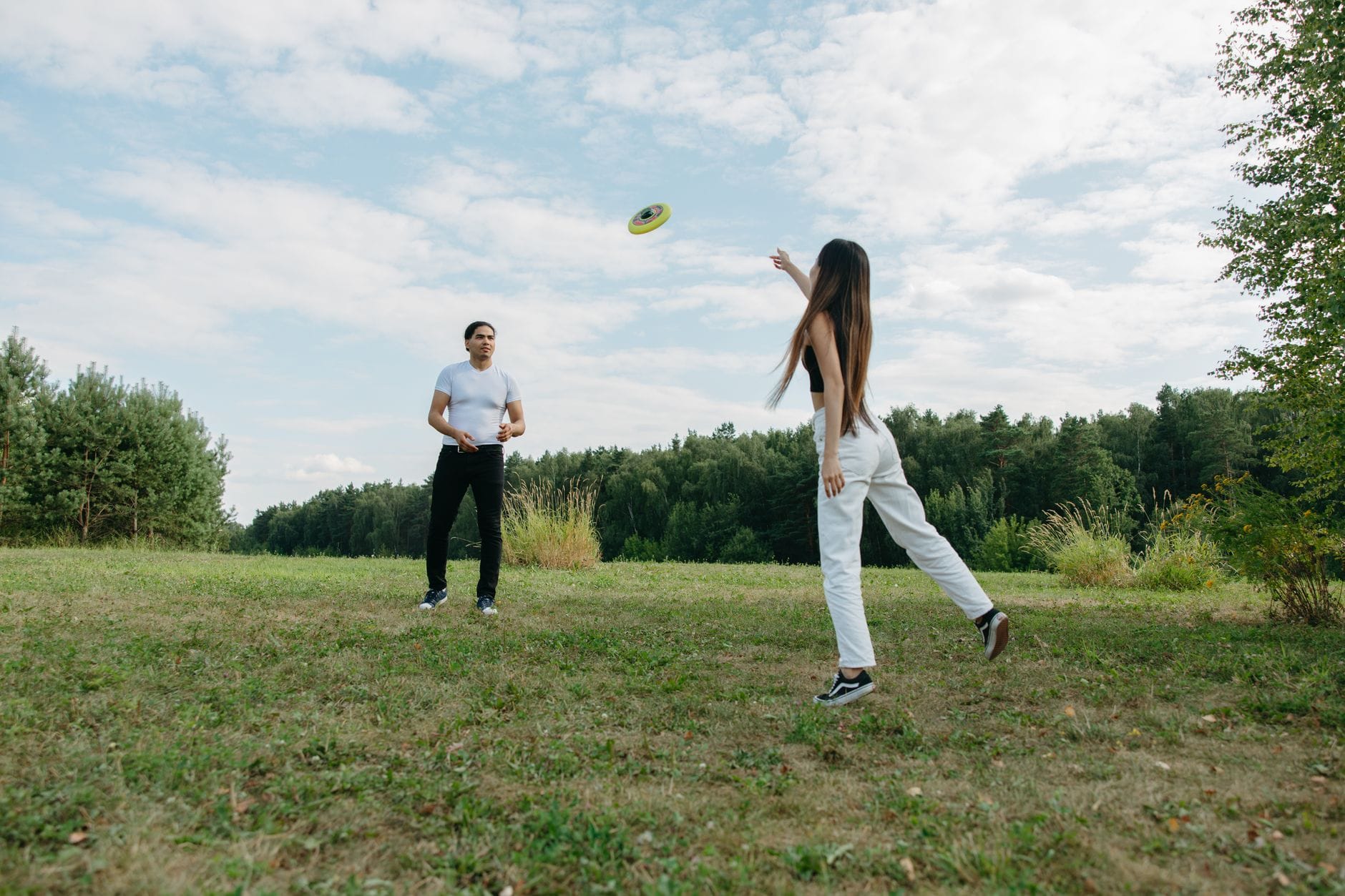 Para rzuca frisbee w słonecznym, zielonym parku